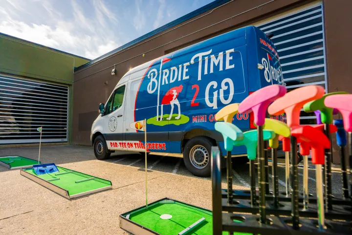 Front view of a traveling 9-hole mini golf course set up outdoors with colorful holes and