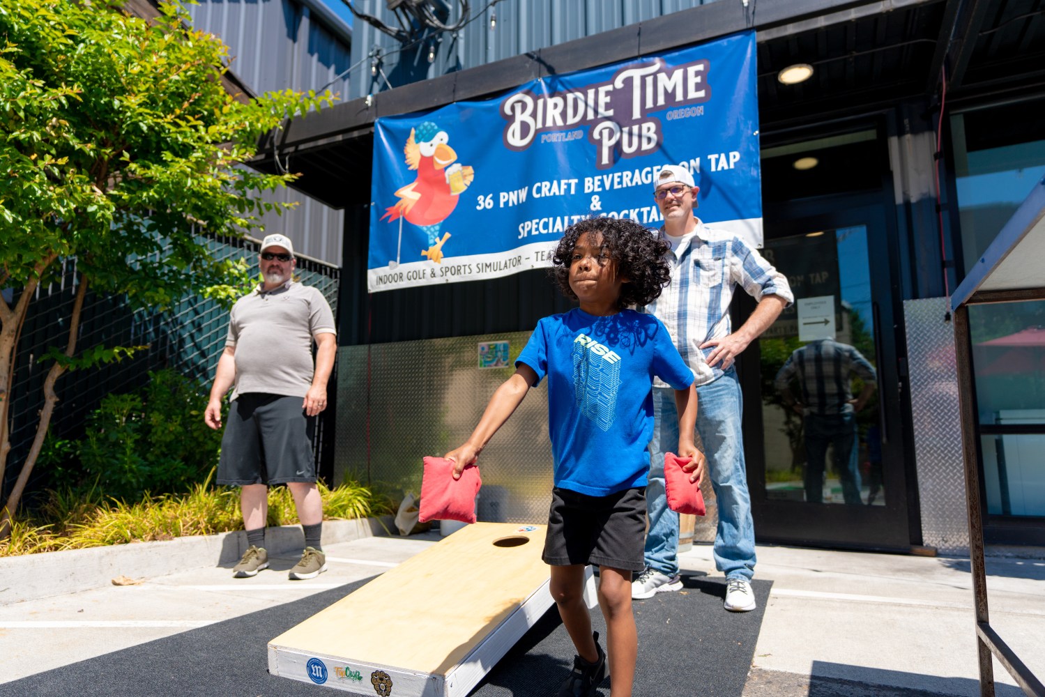 Kid playing corn hole outside 