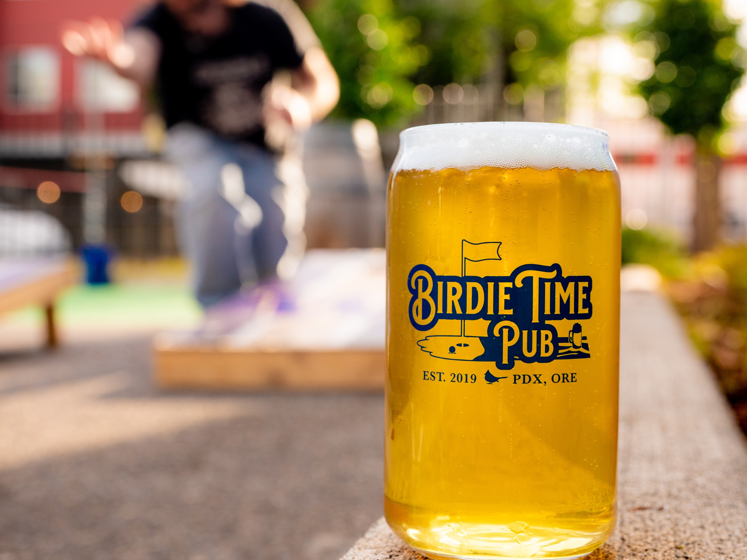Beer on patio with person playing cornhole