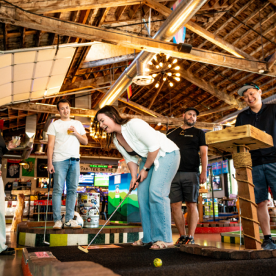 Someone laughing doing a team day and playing mini golf with a group of people.