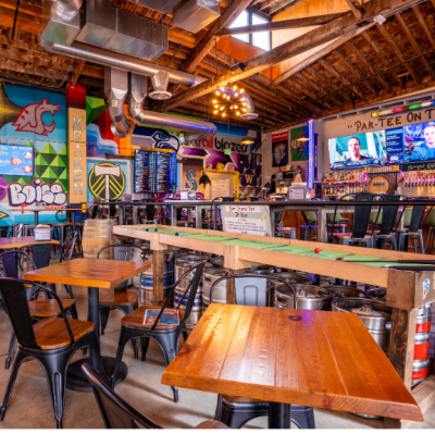 a mini golf bar with seating in an open warehouse space