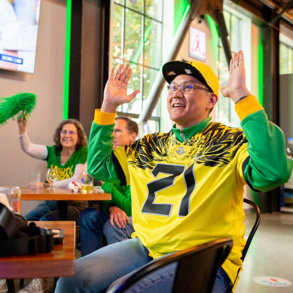 Person with arms up wearing Oregon Ducks jersey.