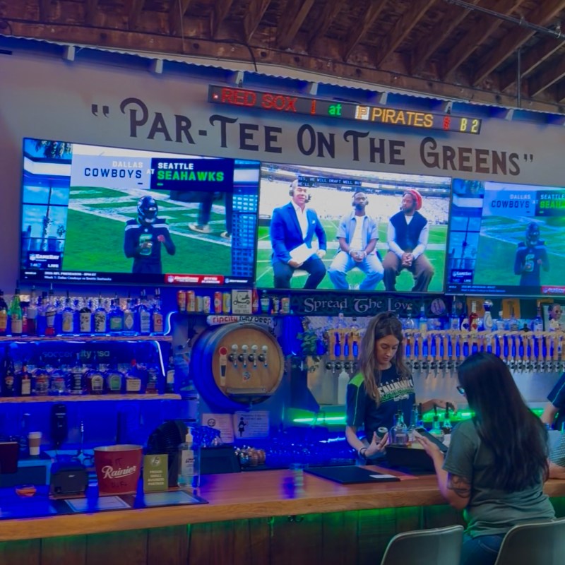 Sports bar with TV screens showing a football game and people at the counter.